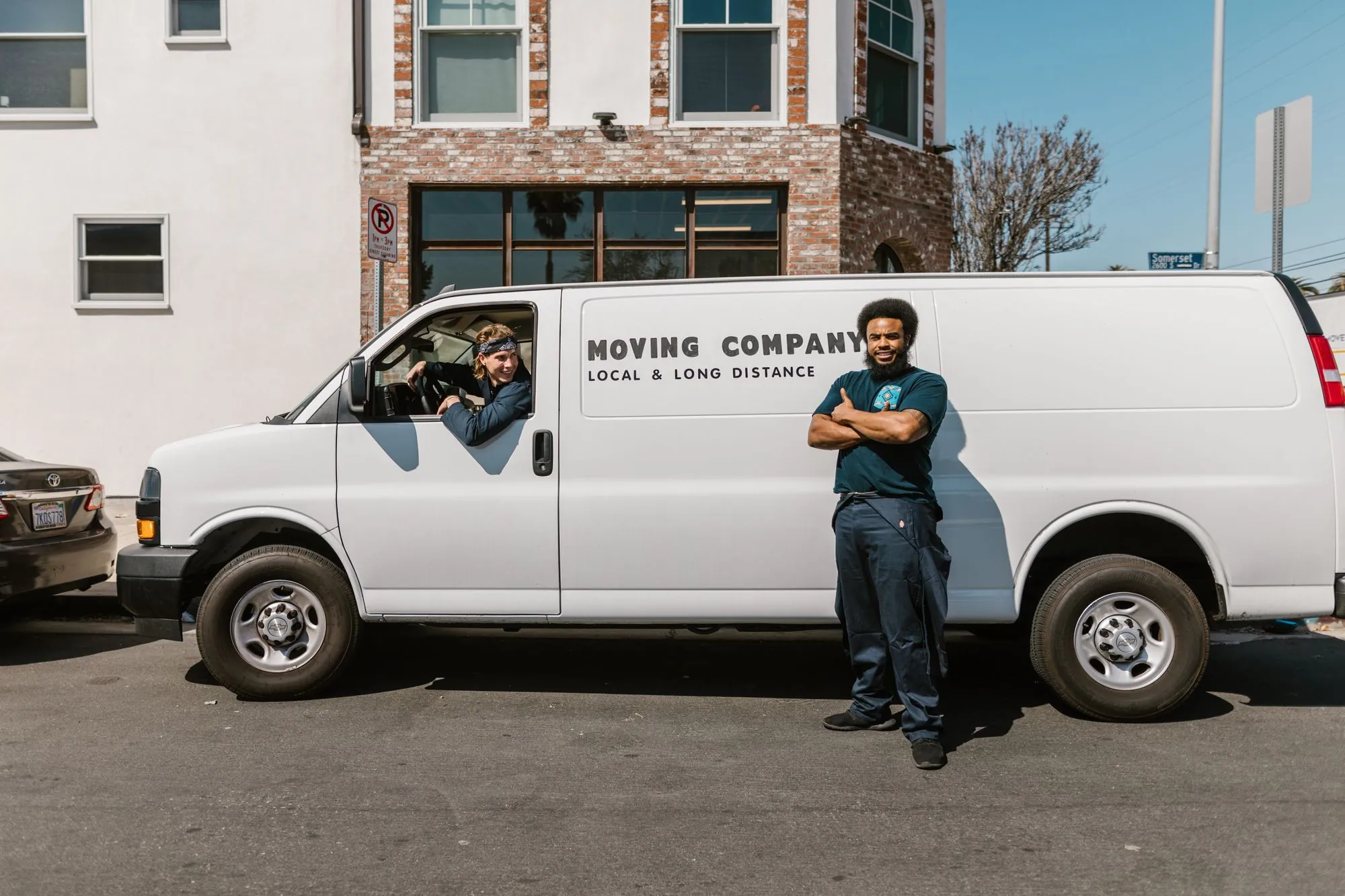 Mover standing next to a white moving van parked at the curb